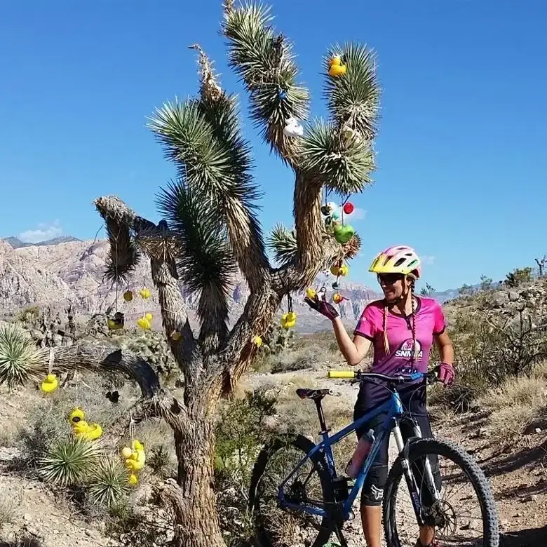Rider posing with a Joshua tree decorated with rubber ducks